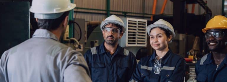 Werksleiter leitet eine Teambesprechung mit Industriearbeitern und organisiert die Personaleinsatzplanung in der Fertigung